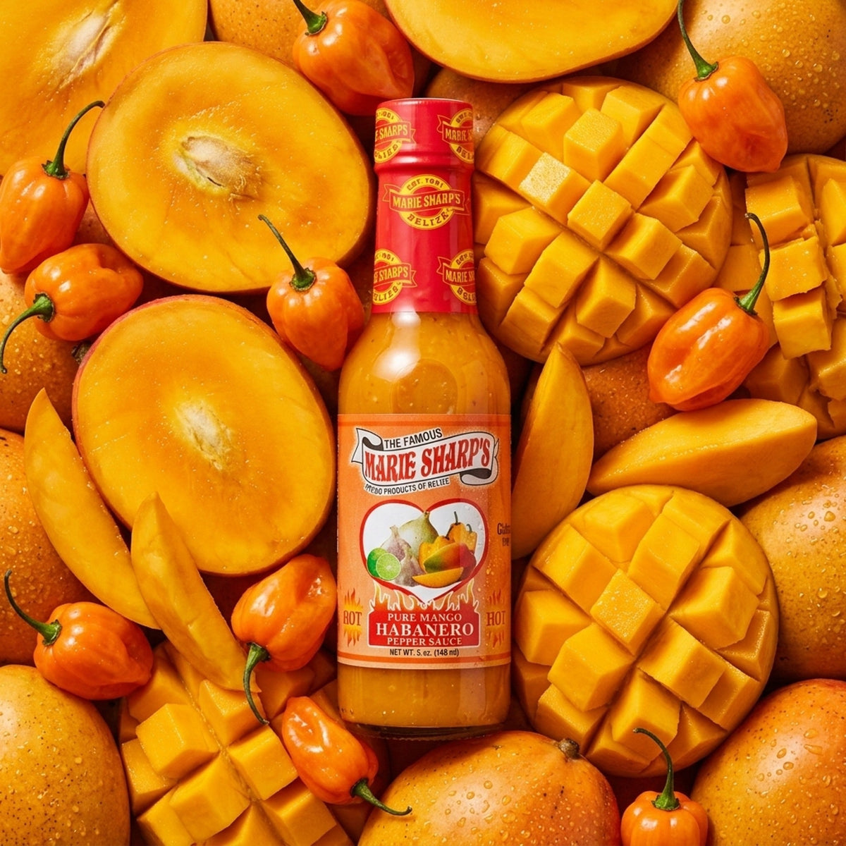 Marie Sharp's Mango Habanero ανάμεσα σε ώριμα μάνγκο και κίτρινες πιπεριές habanero